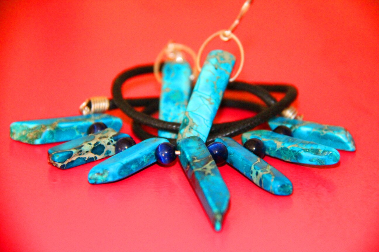 Turquoise-coloured necklace and earrings on a red surface