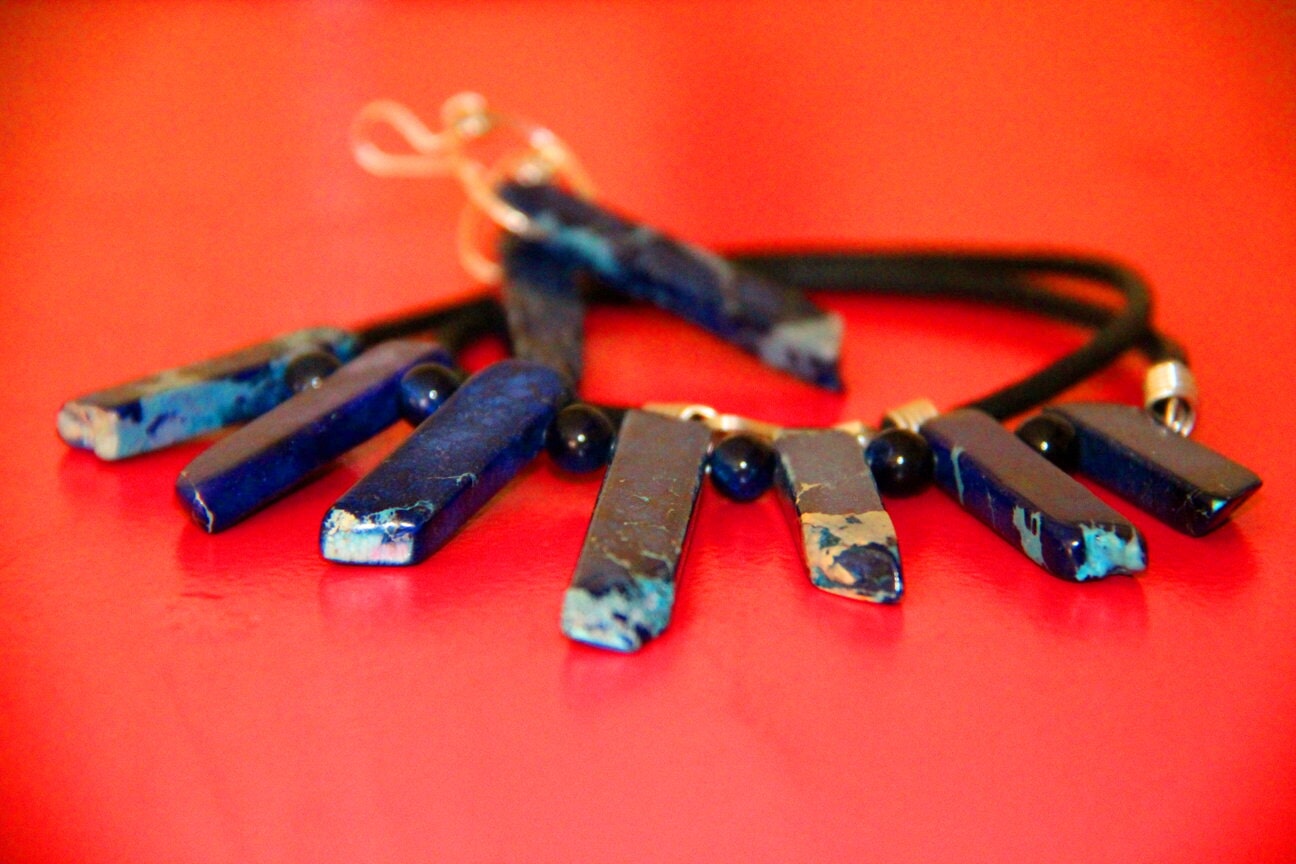 Blue necklace and earrings on a red surface